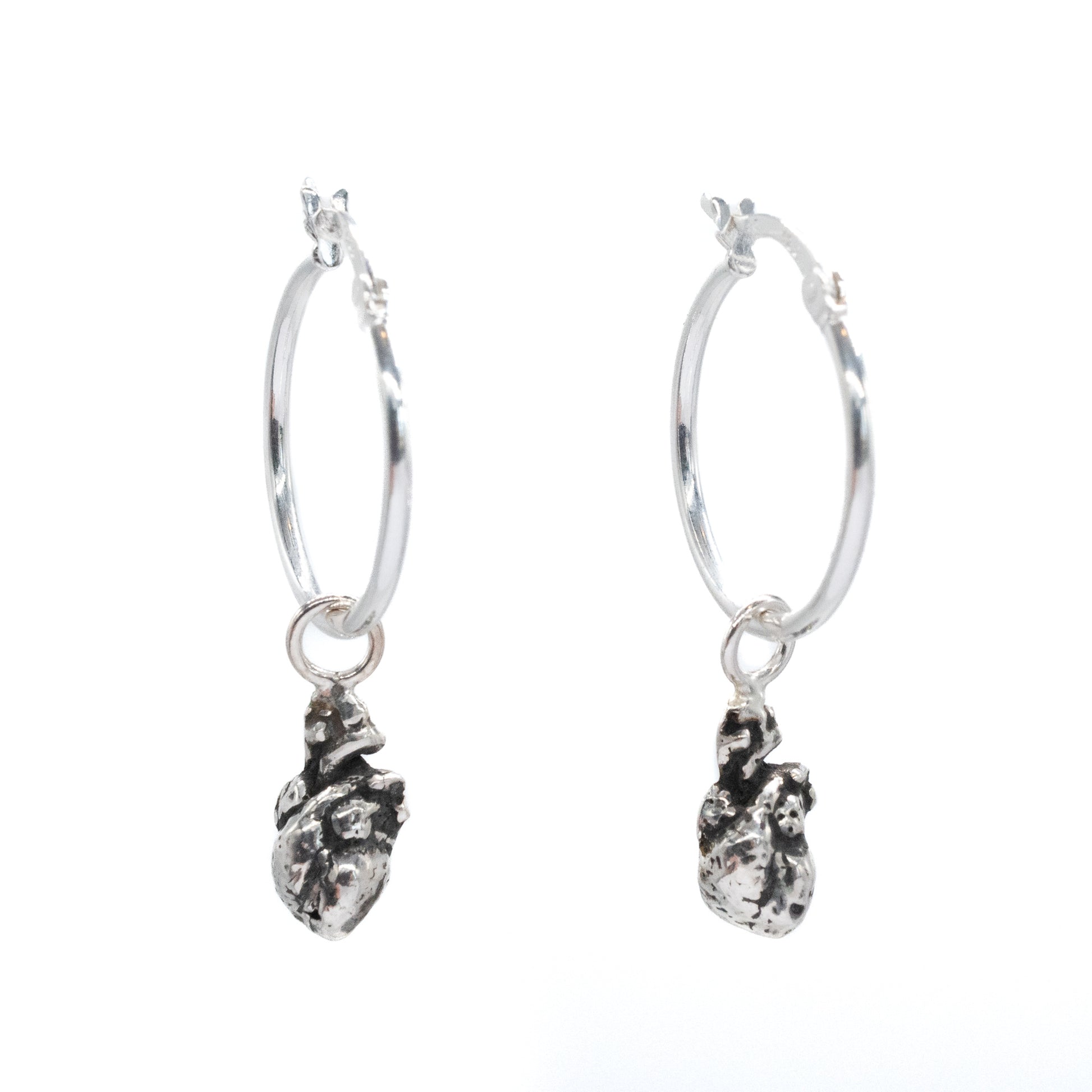 Silver hoop earrings with dangling heart-shaped charms on a white background