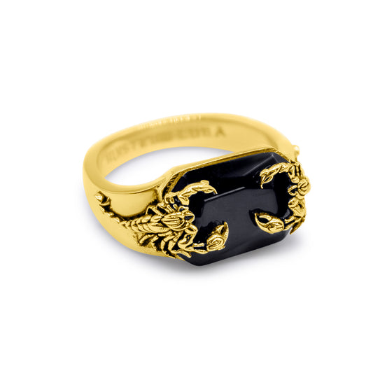 Gold ring with a black stone and scorpion design on a white background