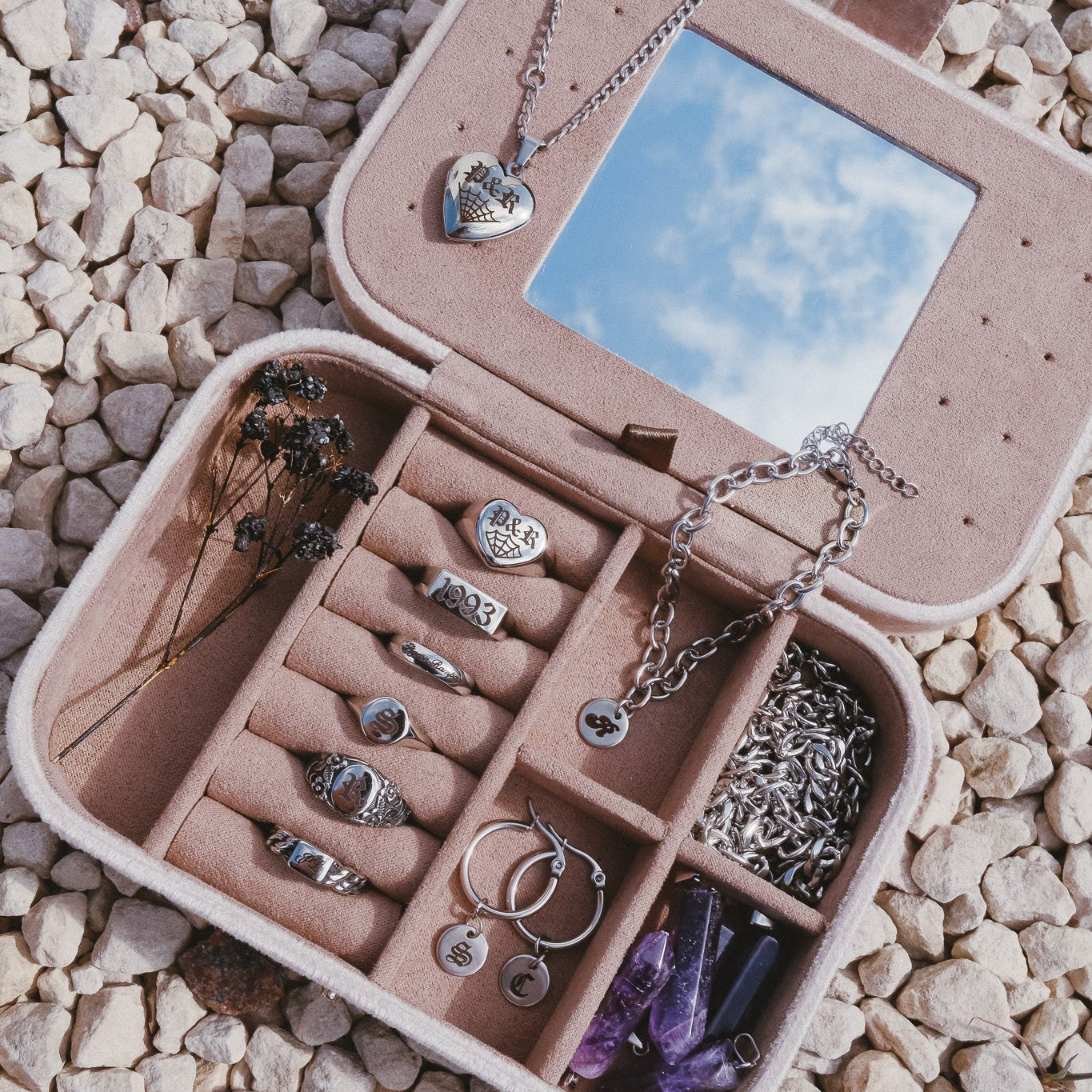 Jewelry organizer with jewelry on a pebbly surface
