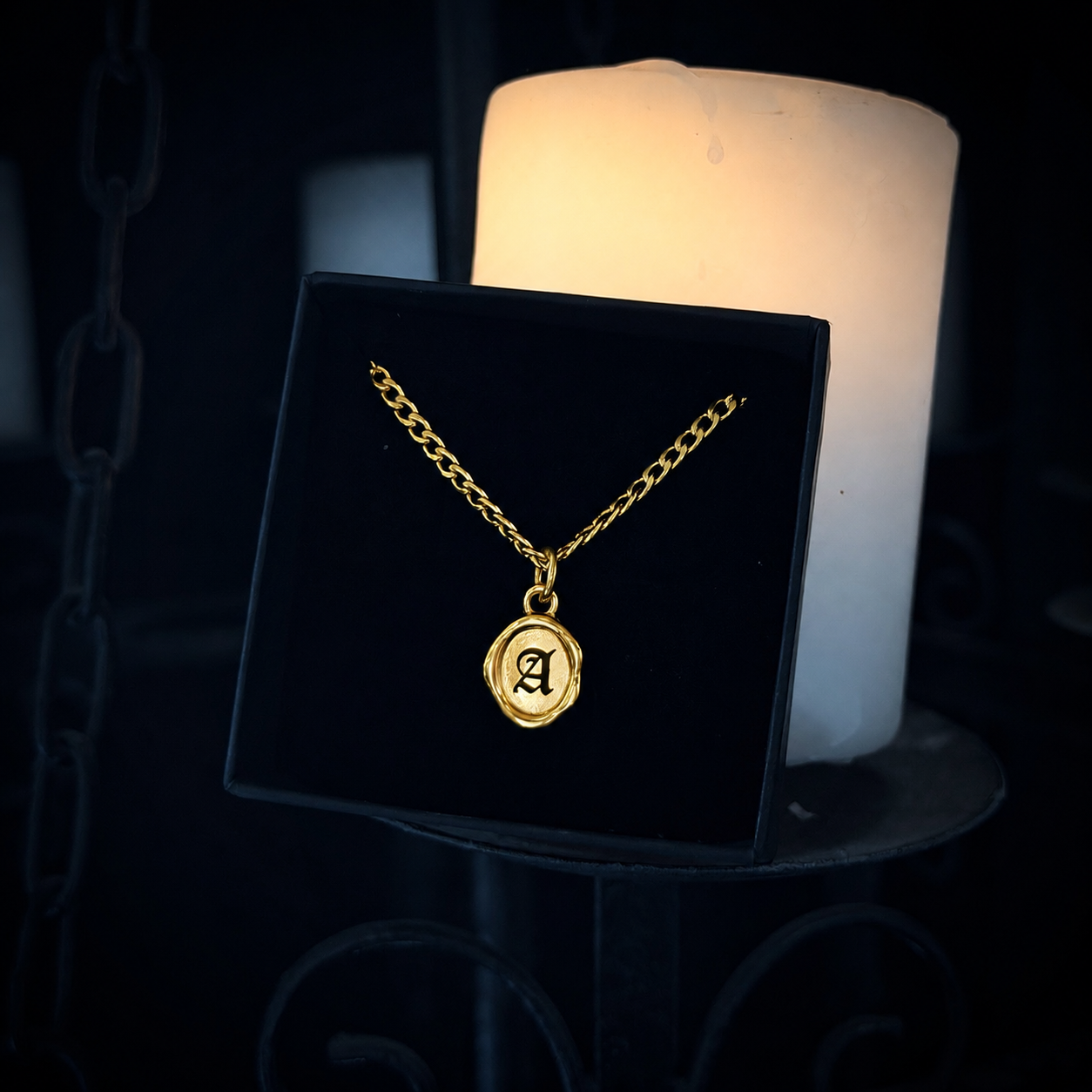 Gold necklace with a pendant featuring the letter 'A' on a black stand with a candle in the background.