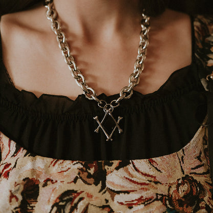Person wearing a floral dress with a black ruffled neckline and a chain necklace.