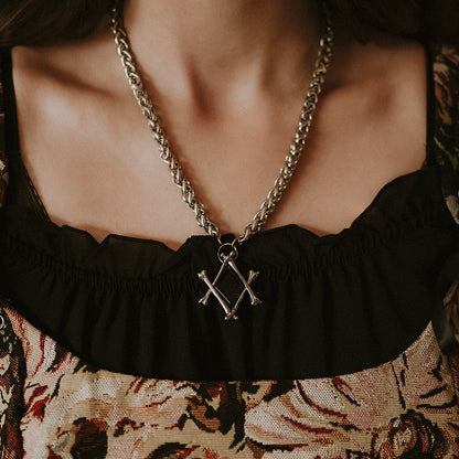 Necklace with a bone pendant worn by a person in a patterned top.