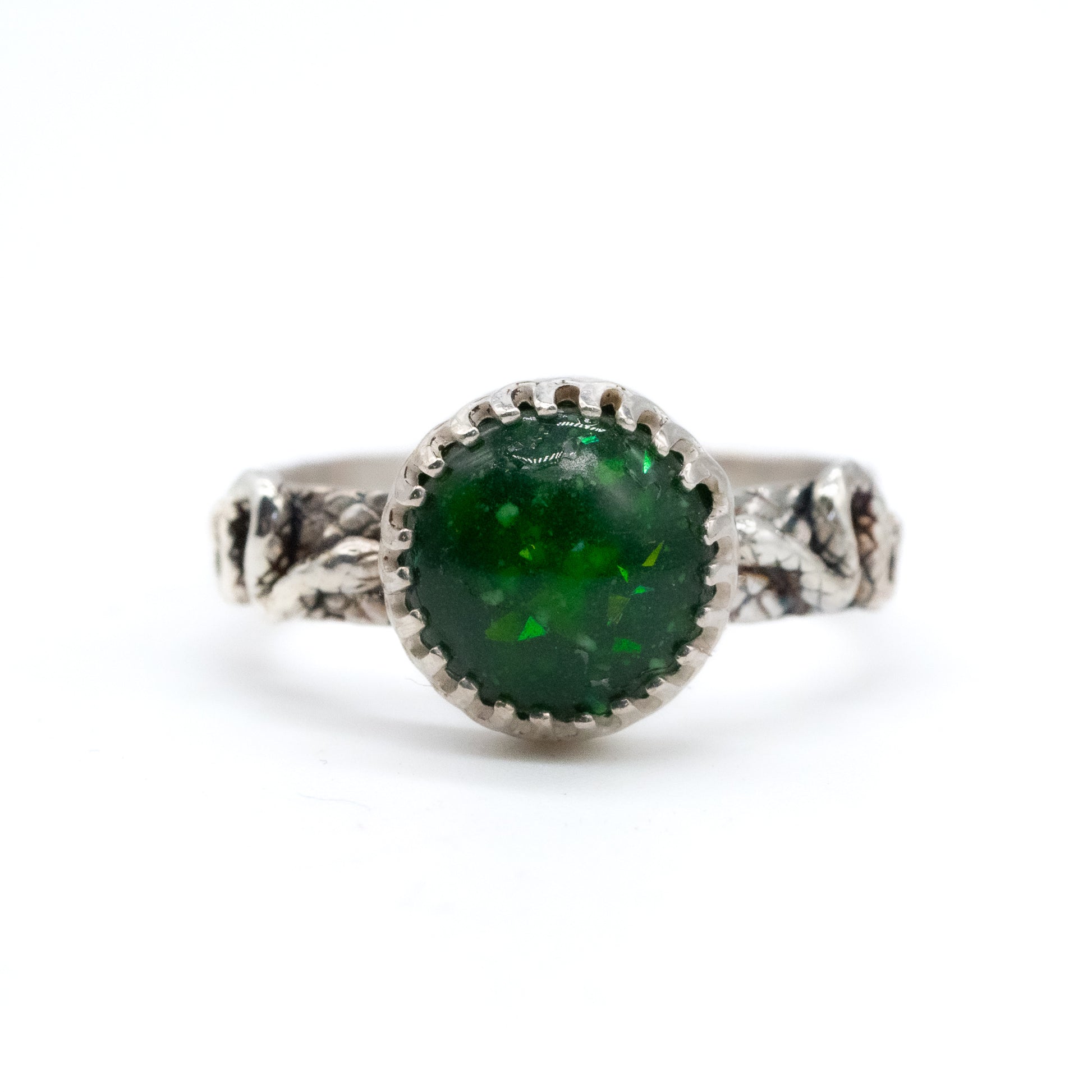 Silver breastmilk ring with a green gemstone on a white background