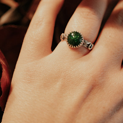 Close-up of a hand wearing a ring with a green gemstone.